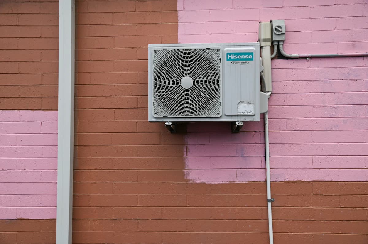 Wandgemonteerde split-airco in een woonkamer met buitenunit zichtbaar door het raam