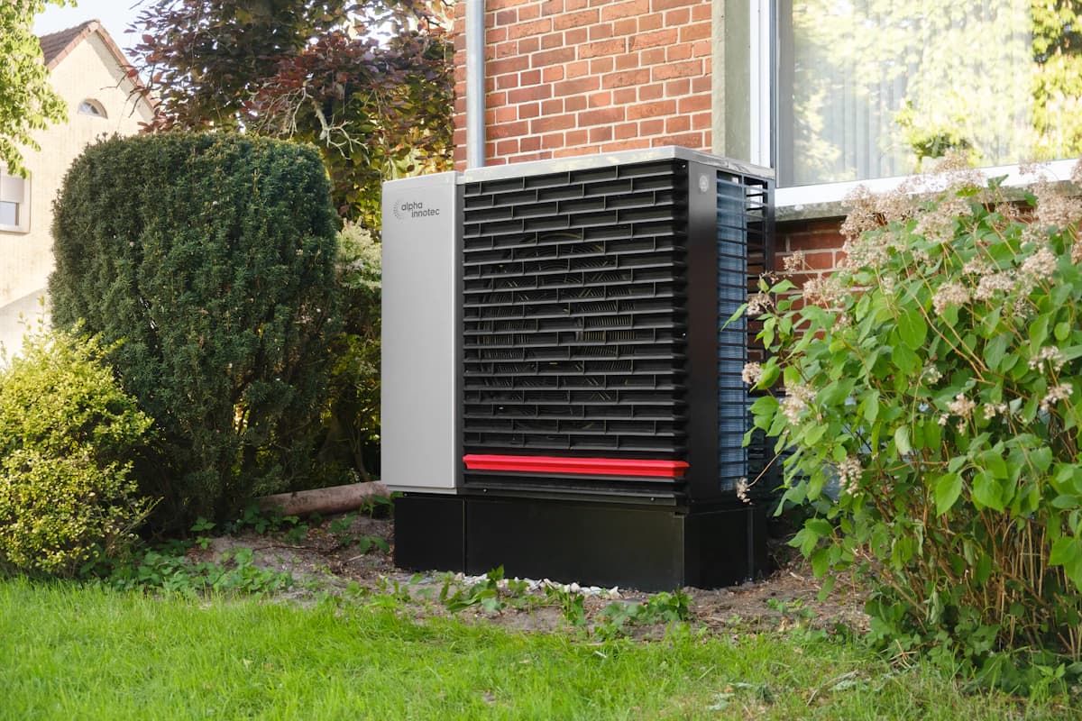 Buitenunit van een warmtepomp-airco langs de gevel van een woning
