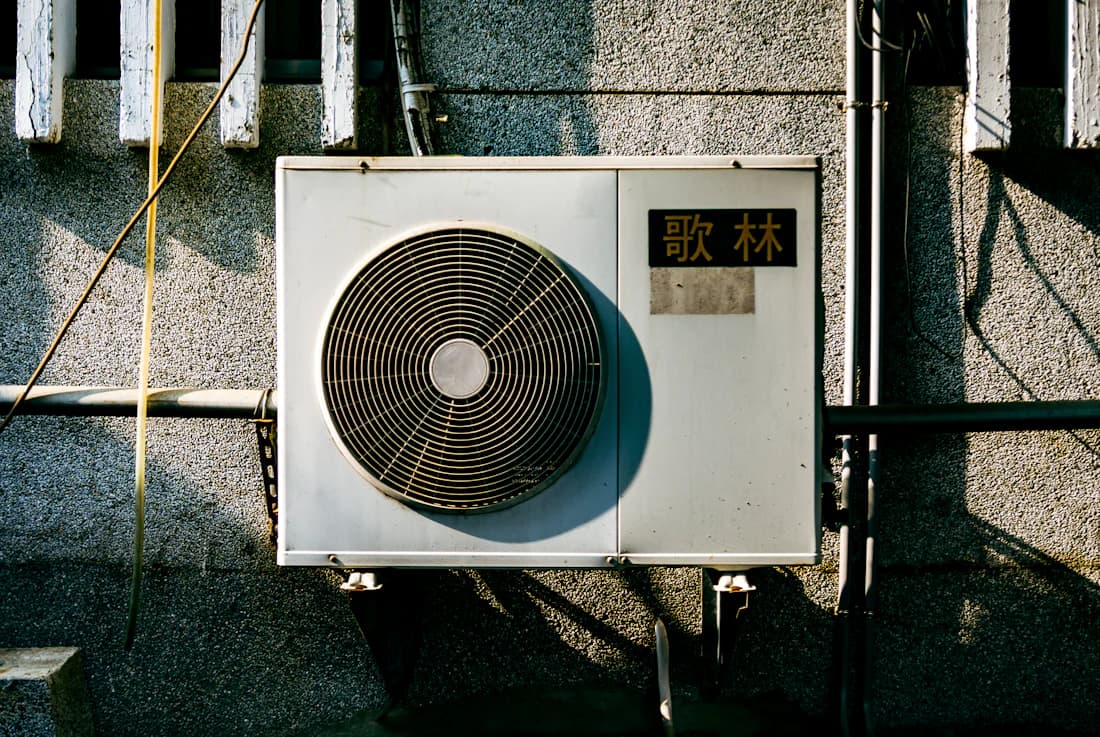 Buitenunit van een hybride warmtepomp tegen de gevel van een woning