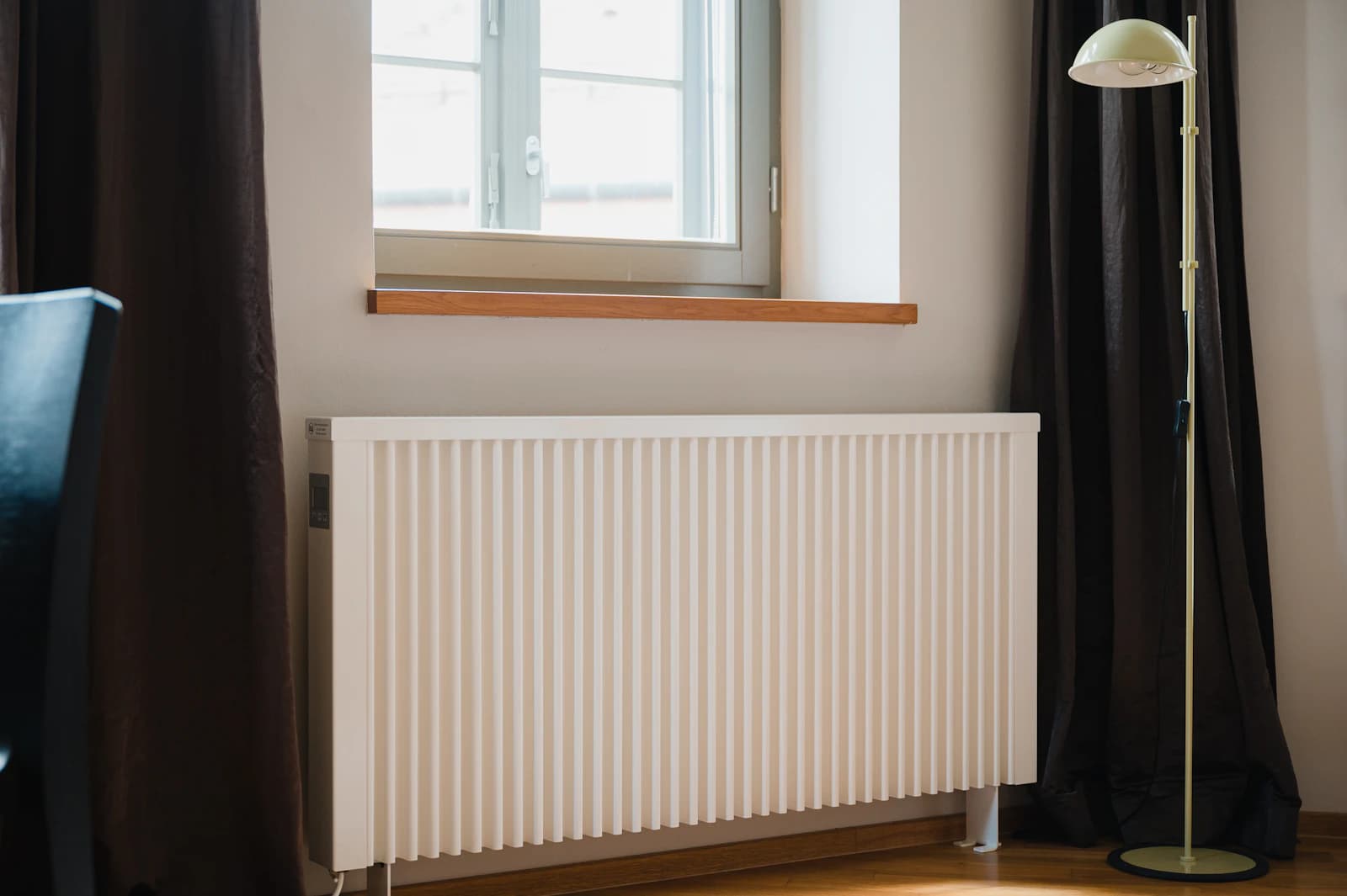 Witte radiator met thermostaatknop en ontluchtventiel waar lucht uit ontsnapt