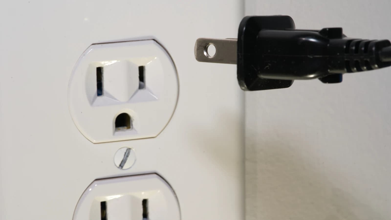 Elektricien installeert een nieuw stopcontact in een witte muur