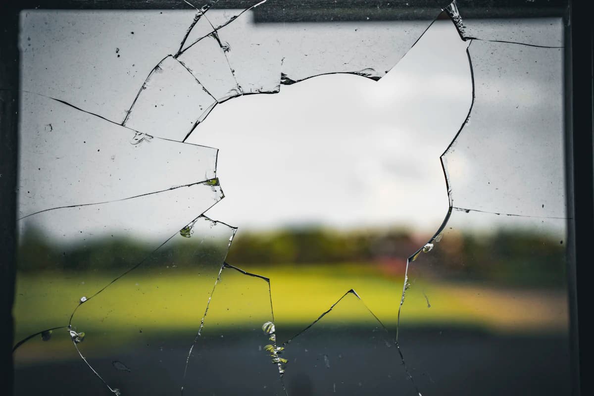 Gebroken ruit met barsten en scherven na breuk in een raam