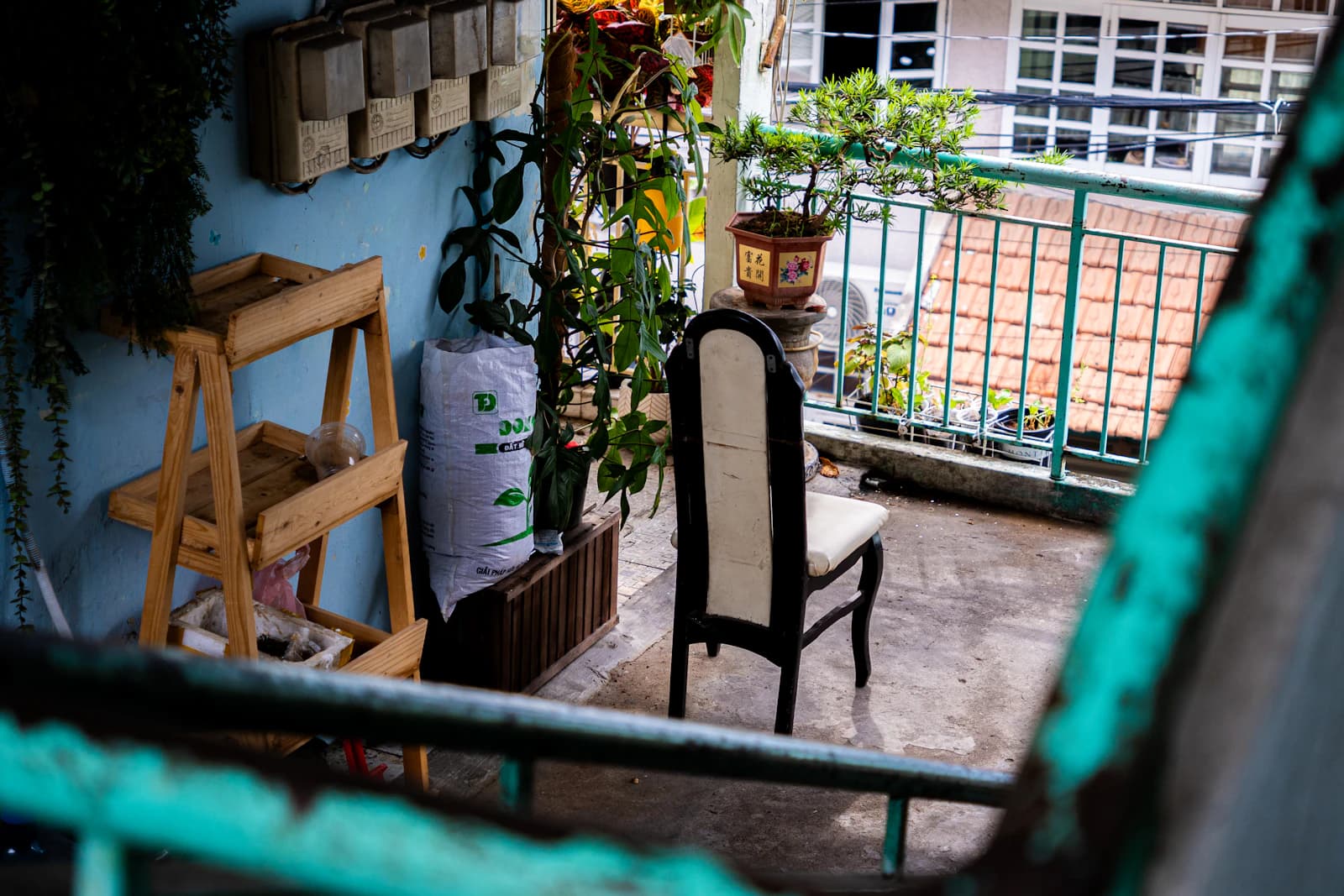Klein stadsbalkon met houten plank, planten in potten en een stoel