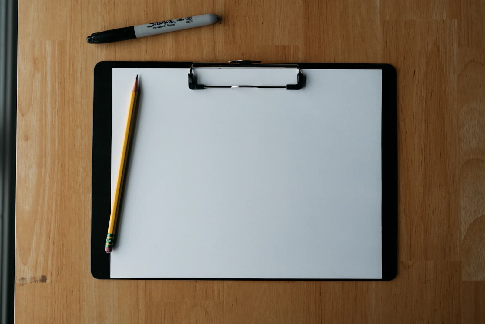 Klembord met checklist en pen op een houten ondergrond, checklist voor het inhuren van een vakman
