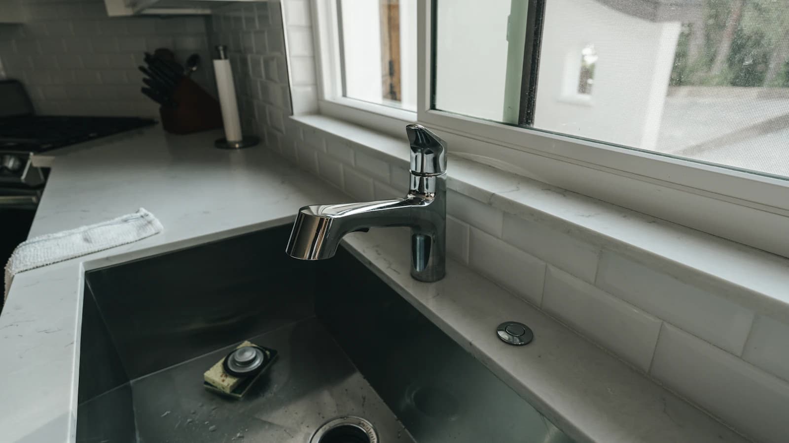 Druppelende keukenkraan met zichtbare waterdruppel boven de spoelbak
