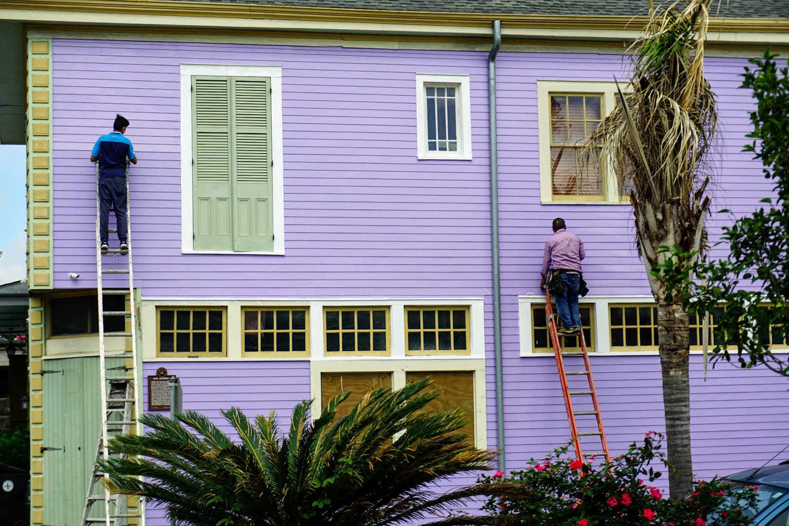 Schilders aan het werk op een ladder tegen de gevel van een Nederlandse woning tijdens buitenschilderwerk
