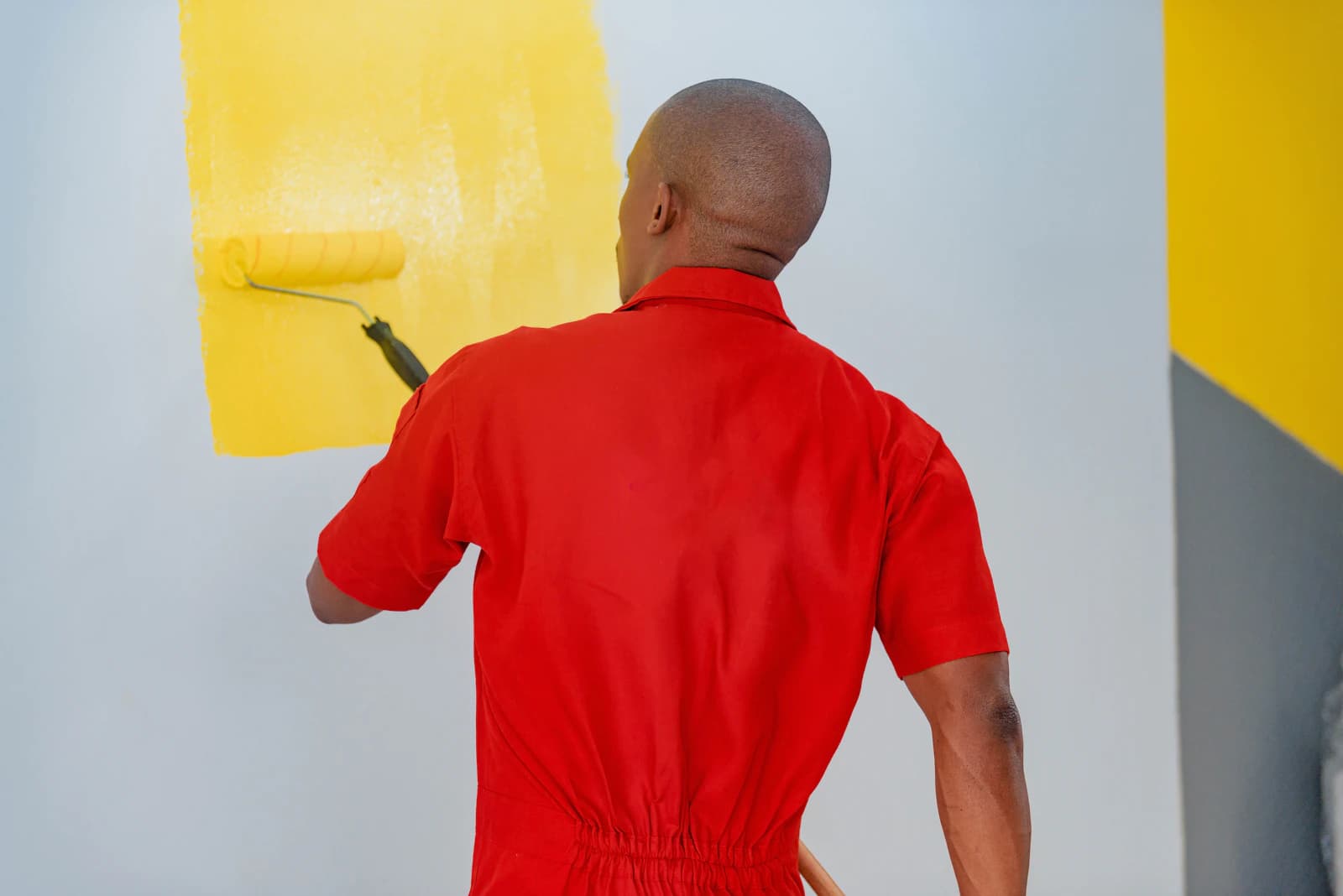 Schilder spuit latex op een muur met een airless spuitpistool tijdens binnenschilderwerk