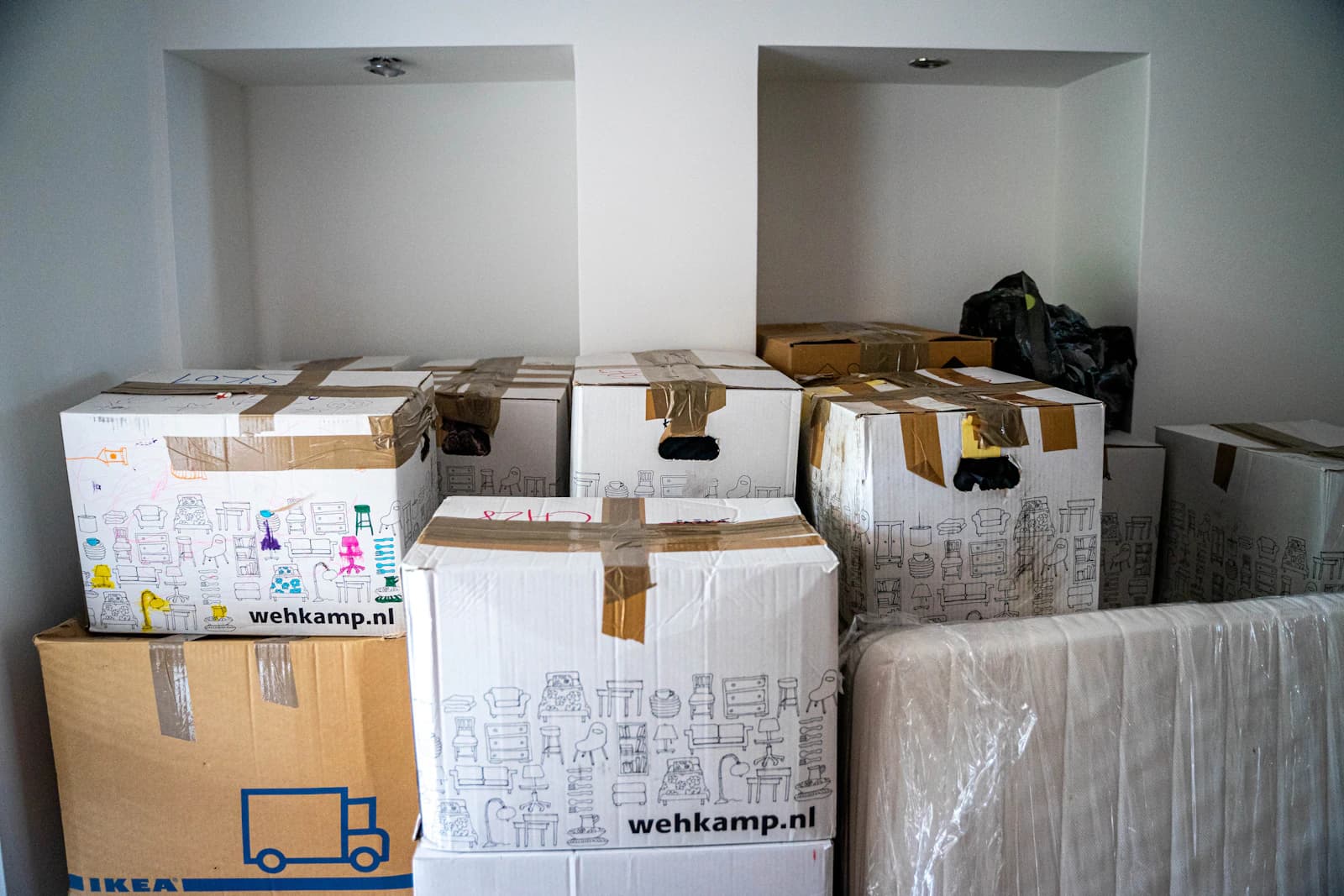 Stapel verhuisdozen en meubels in een woonkamer tijdens een verhuizing