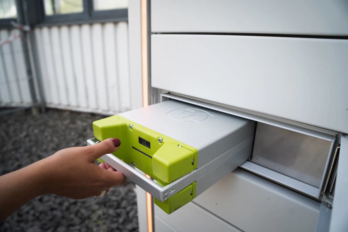 Witte thuisbatterij aan een muur in een technische ruimte, gekoppeld aan een zonnepanelensysteem